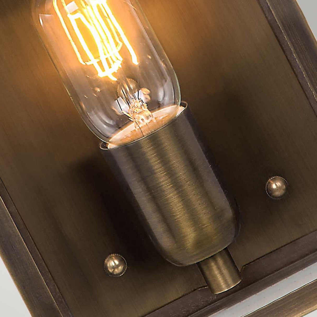 Close-up of a lit Edison-style bulb housed within the Victoria 1 Light Outdoor Wall Light - Verdigris, featuring a solid brass lantern with a verdigris finish that emits a warm glow. This vintage fixture can be mounted on wooden or metallic surfaces, capturing the charm of a Victorian outdoor wall light.