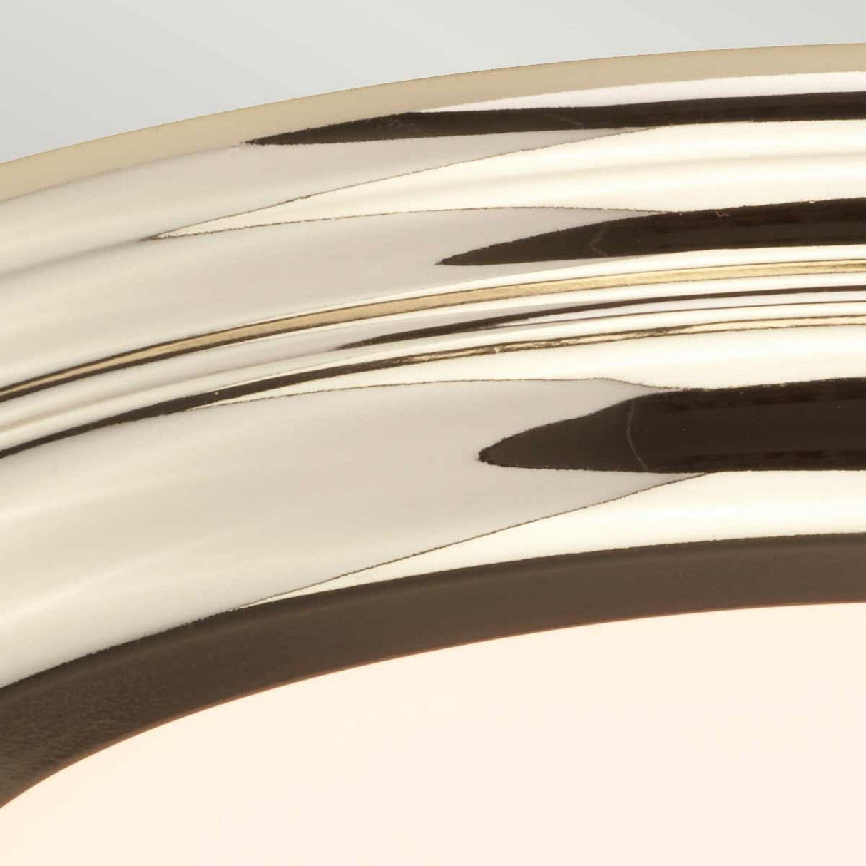 Close-up of the Welland LED Light Flush - Polished Brass, featuring a polished, curved brass frame with a shiny, reflective surface. Set against a pale background, its IP54 rating underscores durability while emphasizing the frame's metallic sheen and subtle LED glow.