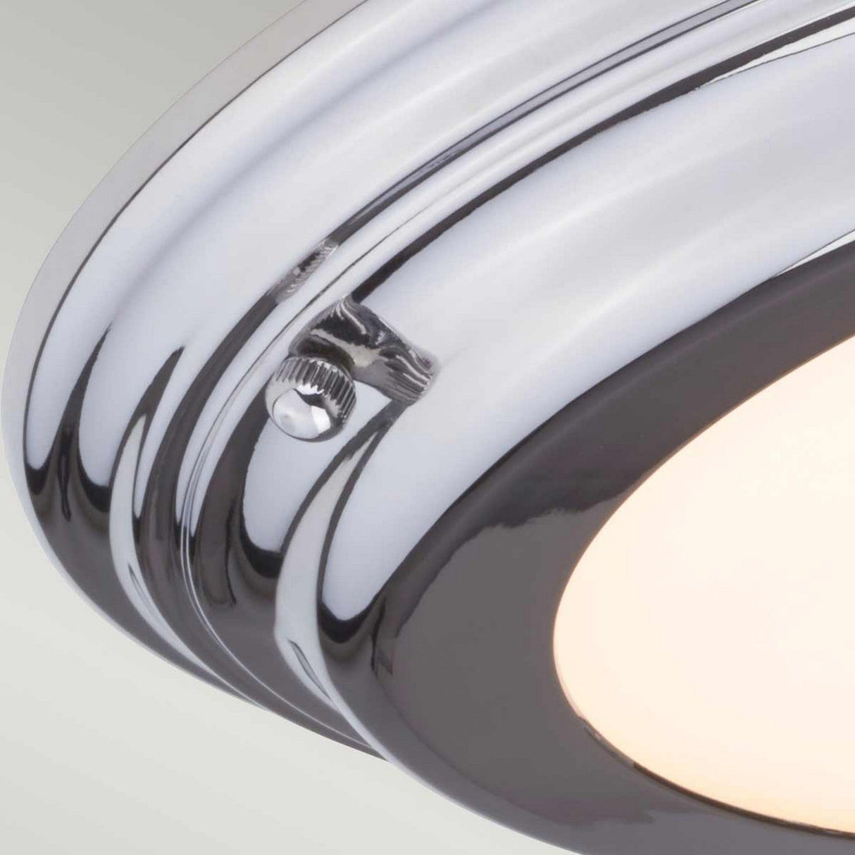 Close-up of the Welland LED Light Flush - Polished Chrome, an IP54-rated ceiling fixture. The light is on, casting a soft glow against its sleek metallic finish.