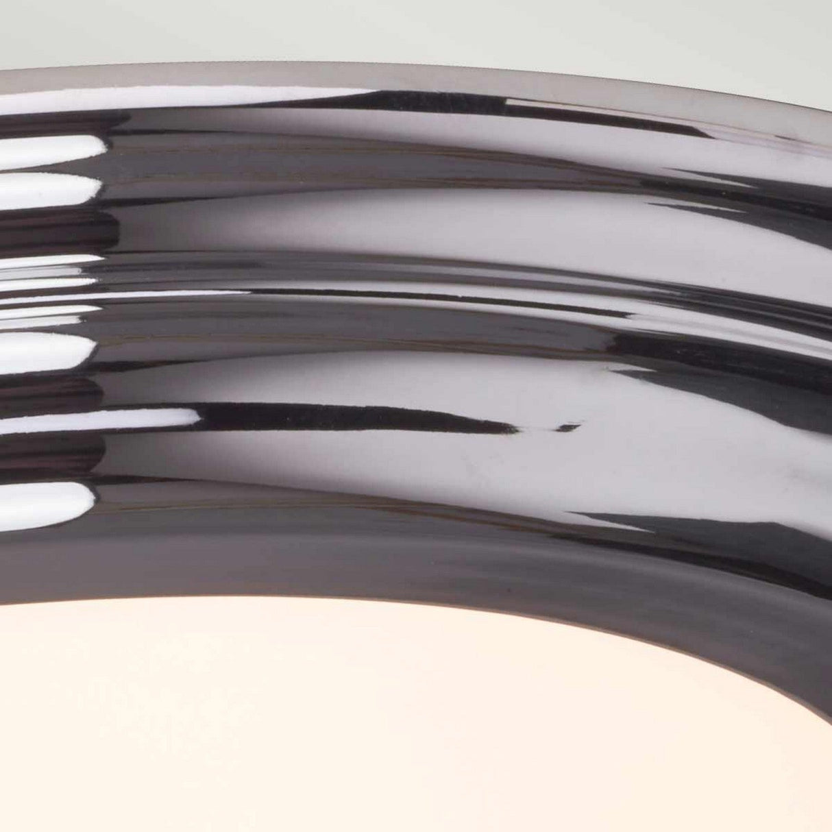 Close-up of a shiny, curved surface in polished chrome reflecting light. The smooth texture and IP54-rated finish create a sleek, modern appearance reminiscent of the Welland LED Light Flush in Polished Chrome.