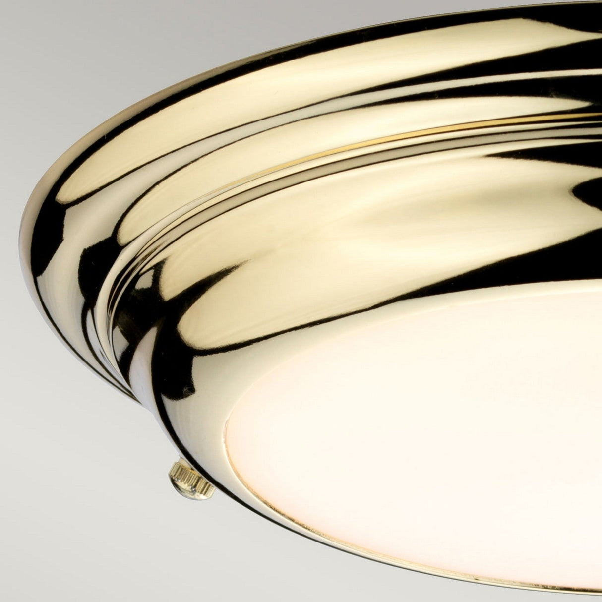 A close-up of the Welland LED Light Mini Flush - Polished Brass ceiling fixture reveals its sleek circular design with a smooth finish. Elegantly mounted on a plain, neutral-colored ceiling, it is IP54 rated for enhanced durability.