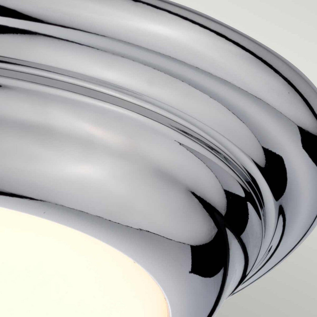 Close-up of the Welland LED Light Mini Flush, featuring a sleek and modern design with a polished chrome rim and a softly glowing LED surface. Its elegant and reflective mini flush design accentuates the gentle curves of the metal.