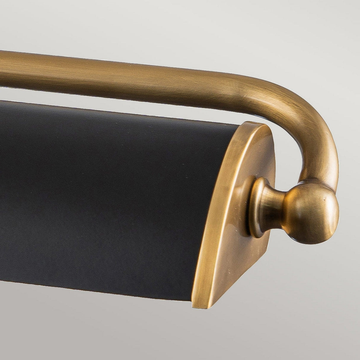 Close-up of the Winchfield 4 Light Large Picture Light in aged brass and matte black, showcasing its curved arm and sleek mid-century modern design against a neutral background.
