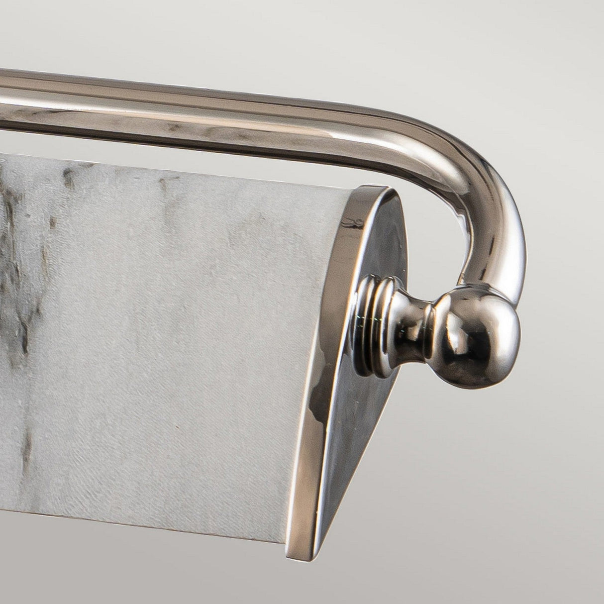 A close-up of the Winchfield 4 Light Large Picture Light in polished nickel and white marble effect, featuring a curved design and shiny finish reminiscent of sophisticated towel bars, with a rolled-up white textured towel resting against it, mounted against a plain background.