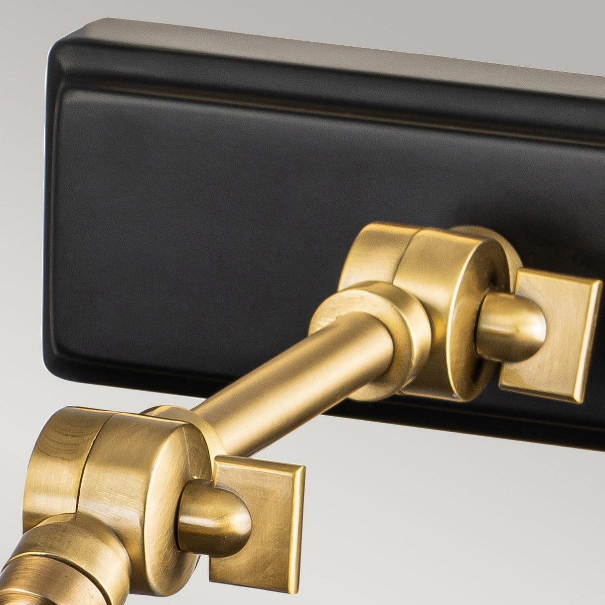 Here is a close-up of the Winchfield 2 Light Medium Picture Light, which combines aged brass with a matte black rectangular base. The lamp includes pivot joints for adjustable positioning, offering a sleek and modern design that emphasizes the contrast between its aged brass and black components.