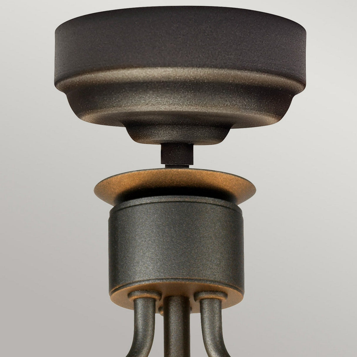 Close-up of the Windsor 3 Light Semi-Flush ceiling fixture in its elegant graphite finish. The stately design showcases a round, textured base with several curving rods extending to the canopy, all against a simple gray backdrop.