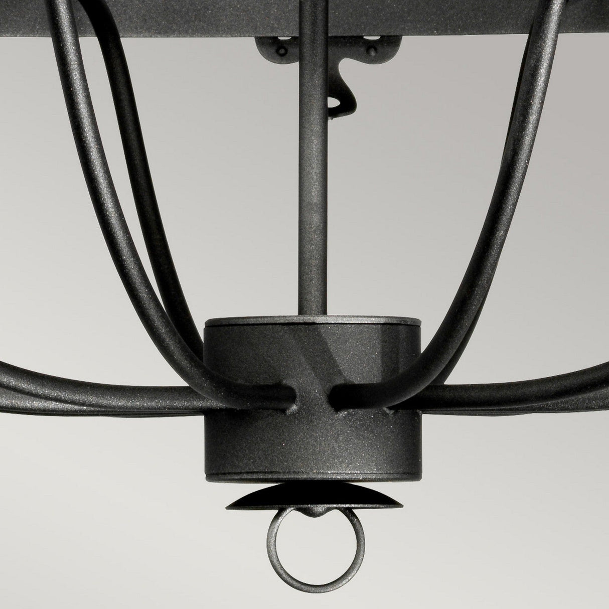 A close-up of an arm on the Windsor 12 Light Chandelier - Graphite highlights its elegant, curved lines and sleek black steel design with a graphite finish. The cylindrical hub and circular hook at the bottom stand out against a light gray background, making it ideal for statement lighting.