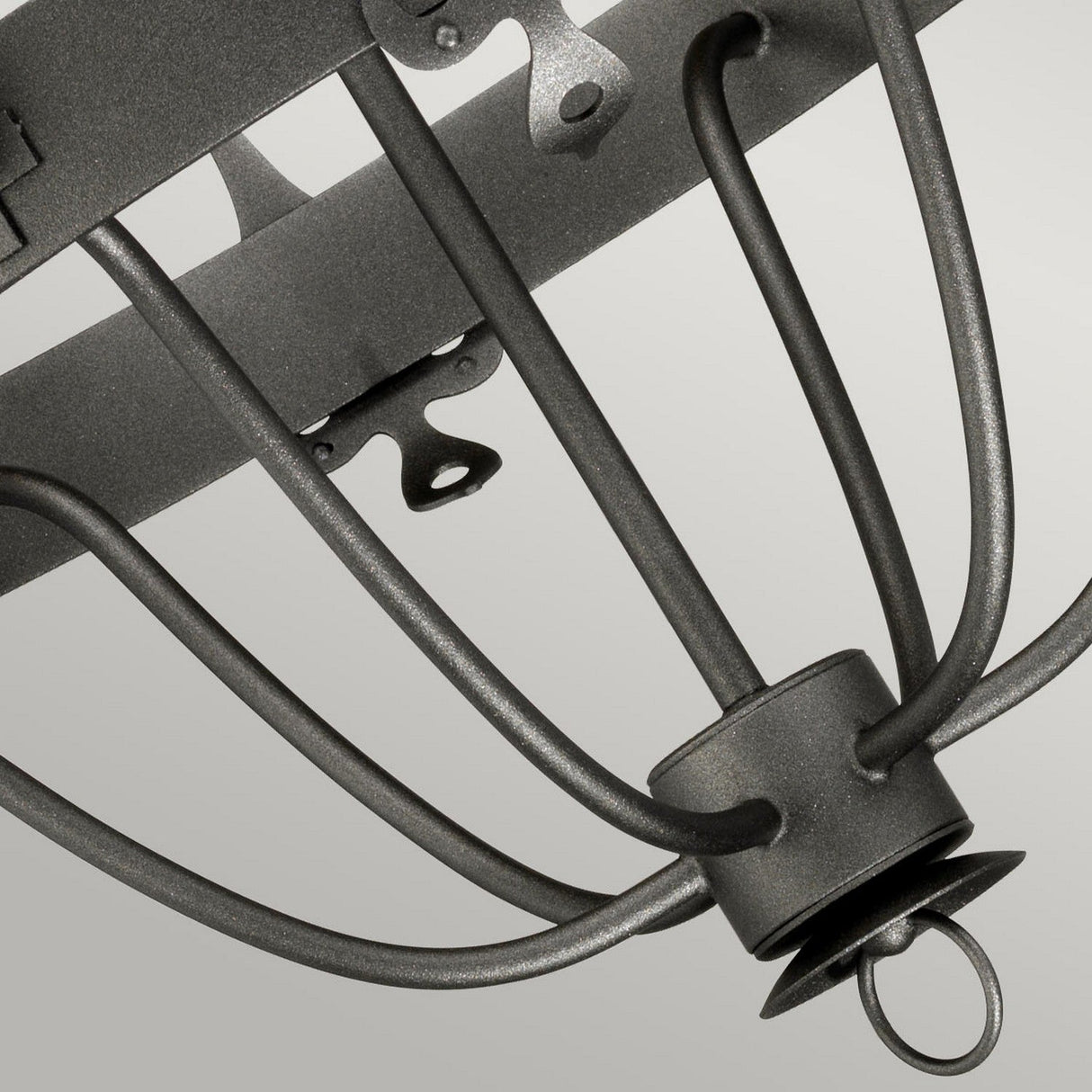 A close-up of the Windsor 6 Light Chandelier in a graphite finish highlights its curved arms and industrial aesthetic, perfectly capturing a modern and minimalist style. The elegant lighting stands out against a light gray background.