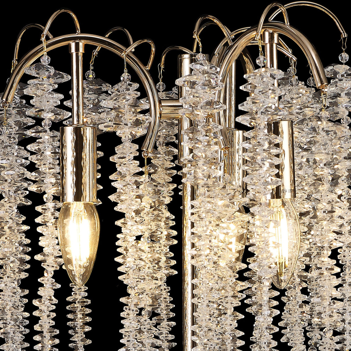Close-up of the Wisteria 3 Light Table Lamp in gold, featuring clear crystal clusters, gold metal arms, and dimmable lighting with two glowing exposed bulbs casting a warm glow through the sparkling crystal accents.