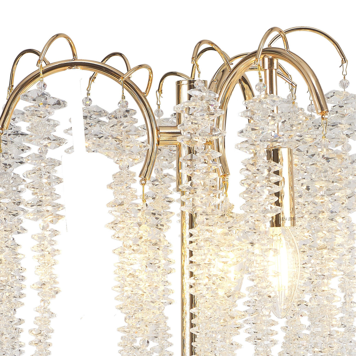 A close-up of the Wisteria 3 Light Table Lamp in gold, showcasing decorative metal arches with hanging clear crystal clusters and exposed LED bulbs that emit a warm, dimmable glow.