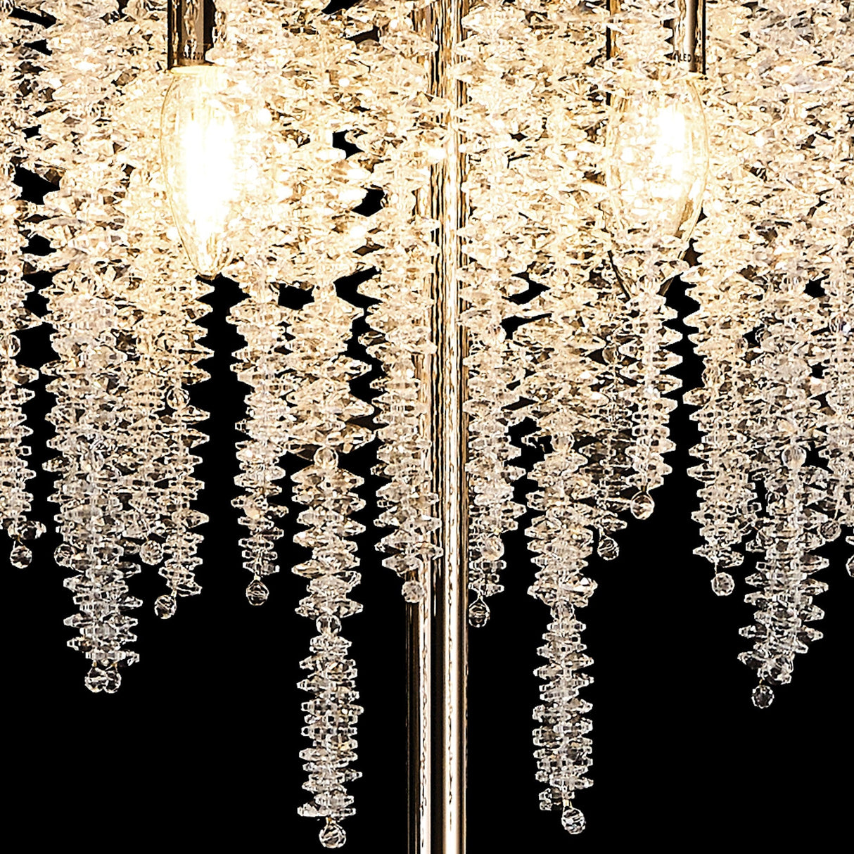 Close-up of the Wisteria 4 Light Crystal Floor Lamp in French Gold, featuring spiral strands of clear crystals illuminated by warm bulbs against a black background, creating elegant ambient lighting.