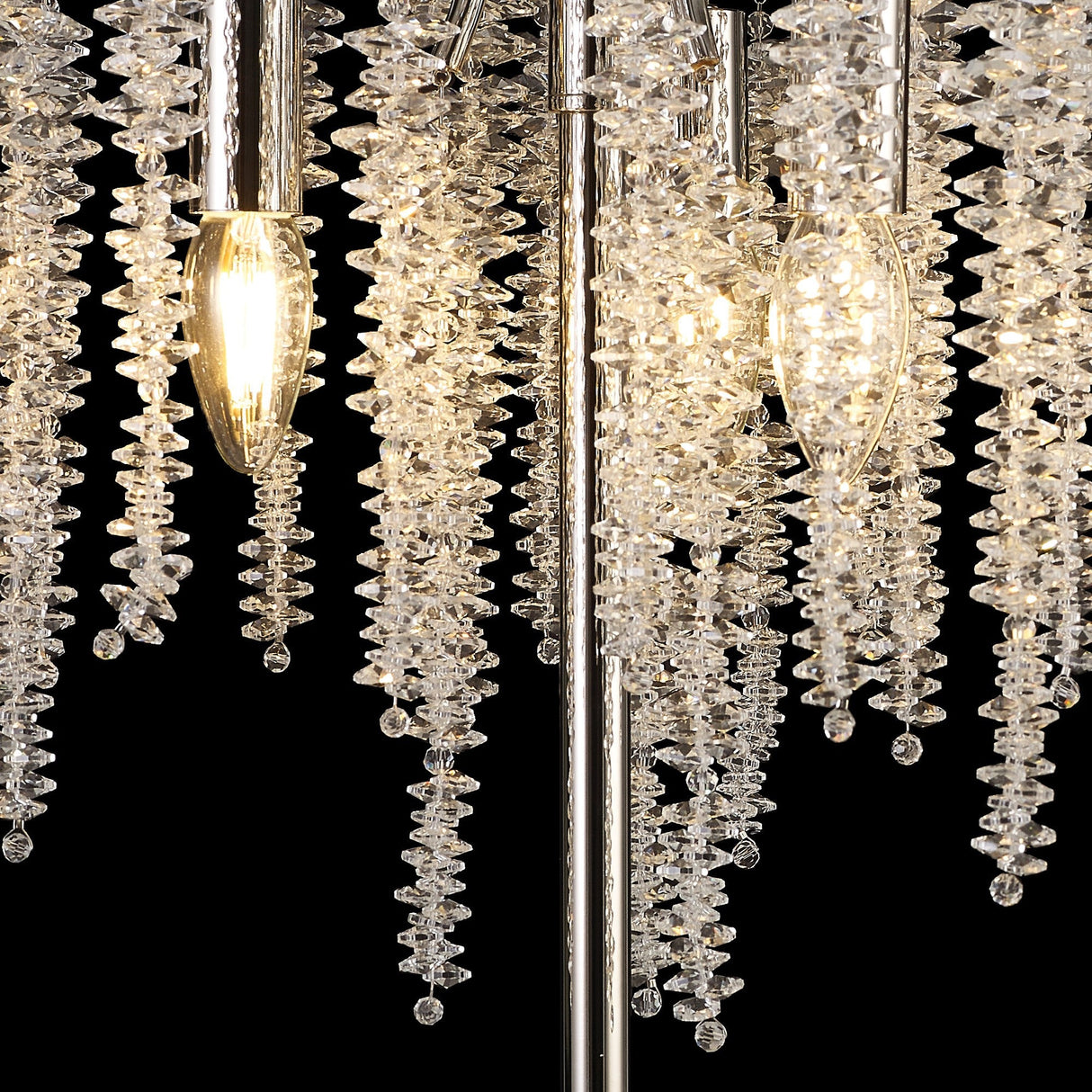 Close-up of the Wisteria 3 Light Table Lamp in nickel, featuring hanging clusters of clear crystals and glowing bulbs. The faceted crystals reflect ambient light, producing a sparkling effect against a black background.