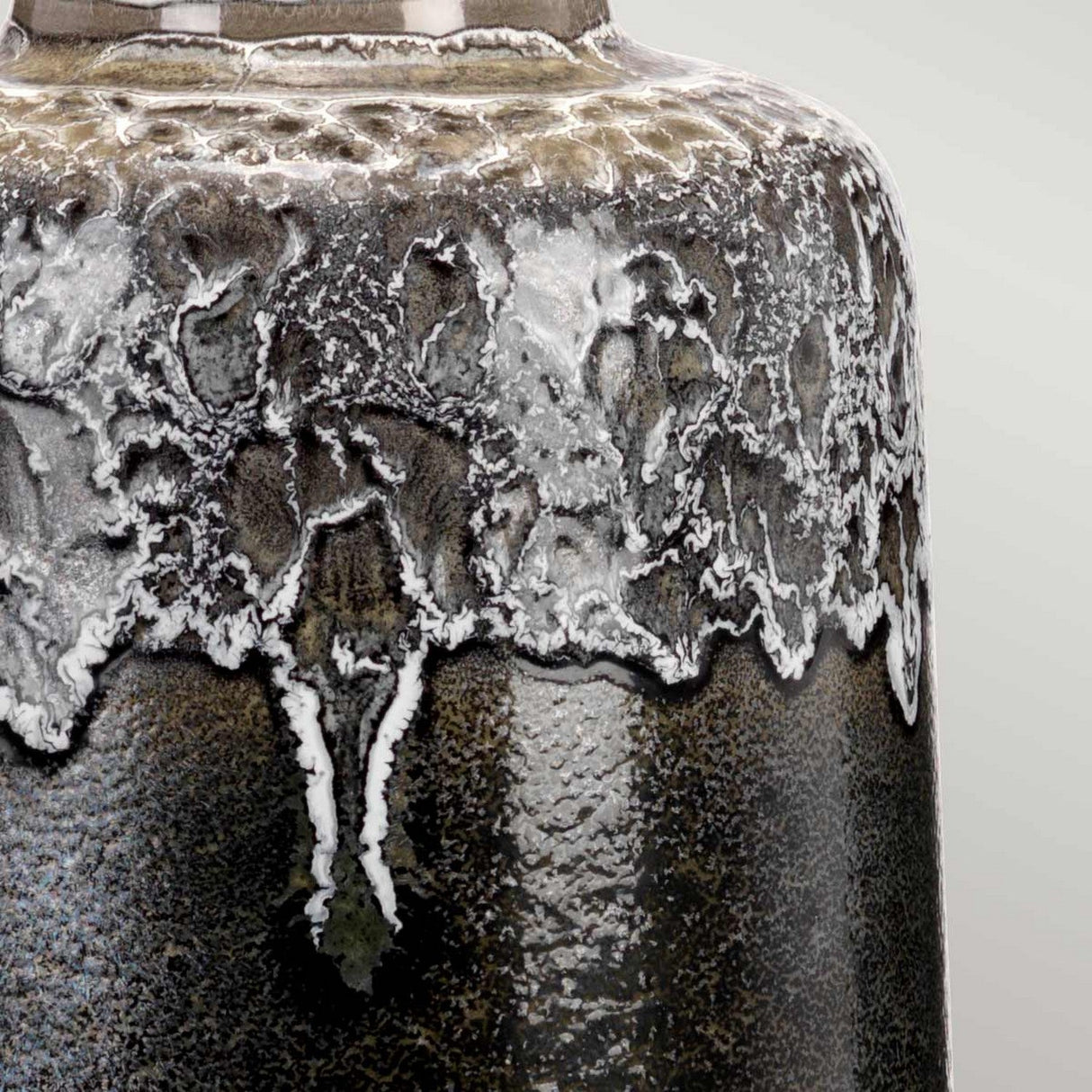 Detailed view of a ceramic vase adorned with a complex, detailed reactive glaze. The exterior showcases a mix of earthy hues interwoven with a rugged, crackled white design descending downwards, akin to the polished texture typically found in the Woolwich 1 Light Table Lamp's textured graphite base.