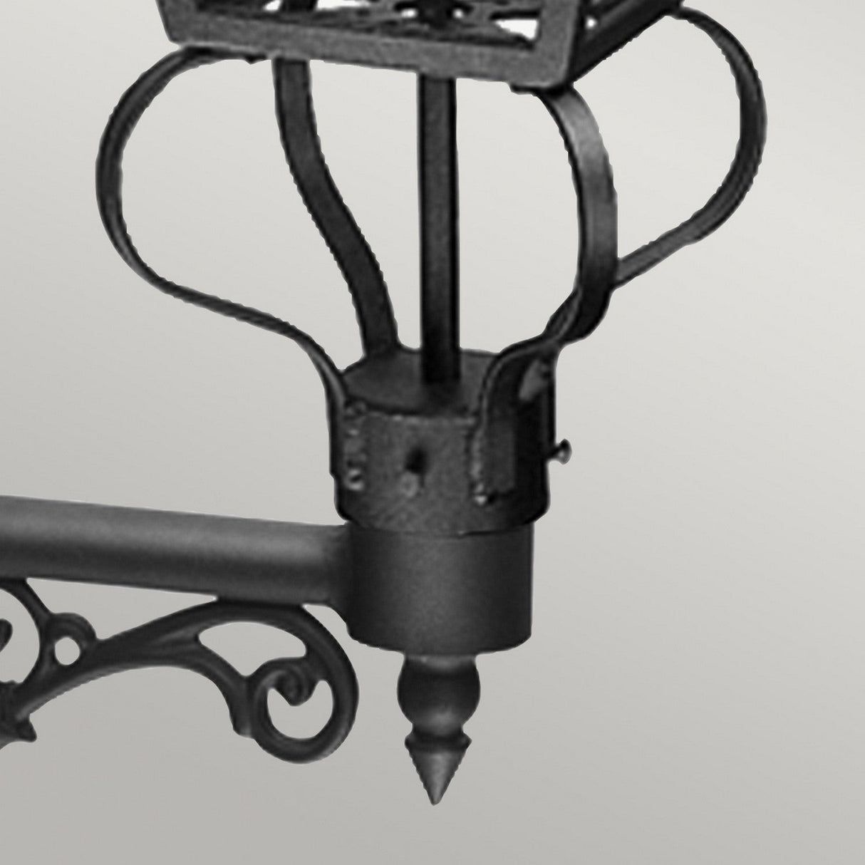 A close-up of the Wilmslow 1 Light Outdoor Wall Light in black, featuring ornate scrollwork and a crown-like design that evokes the style of Victorian street lamps. The light is mounted against a neutral gray background.