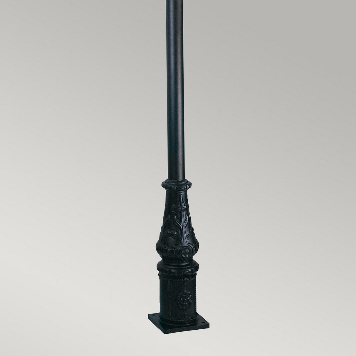 The Wilmslow 1 Light Lamp Post in black features an ornate, decorative base and stands against a plain gray background. Made from durable cast aluminum, this lamp post showcases intricate designs and a sturdy square base, offering a classic or Victorian-inspired style perfect for outdoor lighting scenarios.