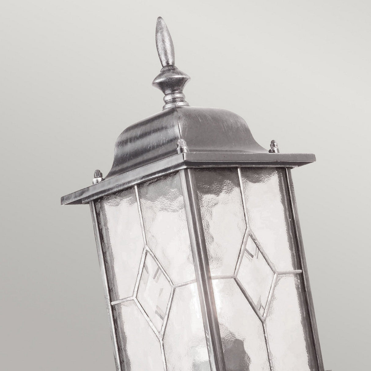 Close-up of the Wexford 1 Light Outdoor Up Wall Light in black and silver, showcasing its ornate frame and leaded glass panels with diamond-shaped patterns, embodying a traditional lantern design against a plain gray background.