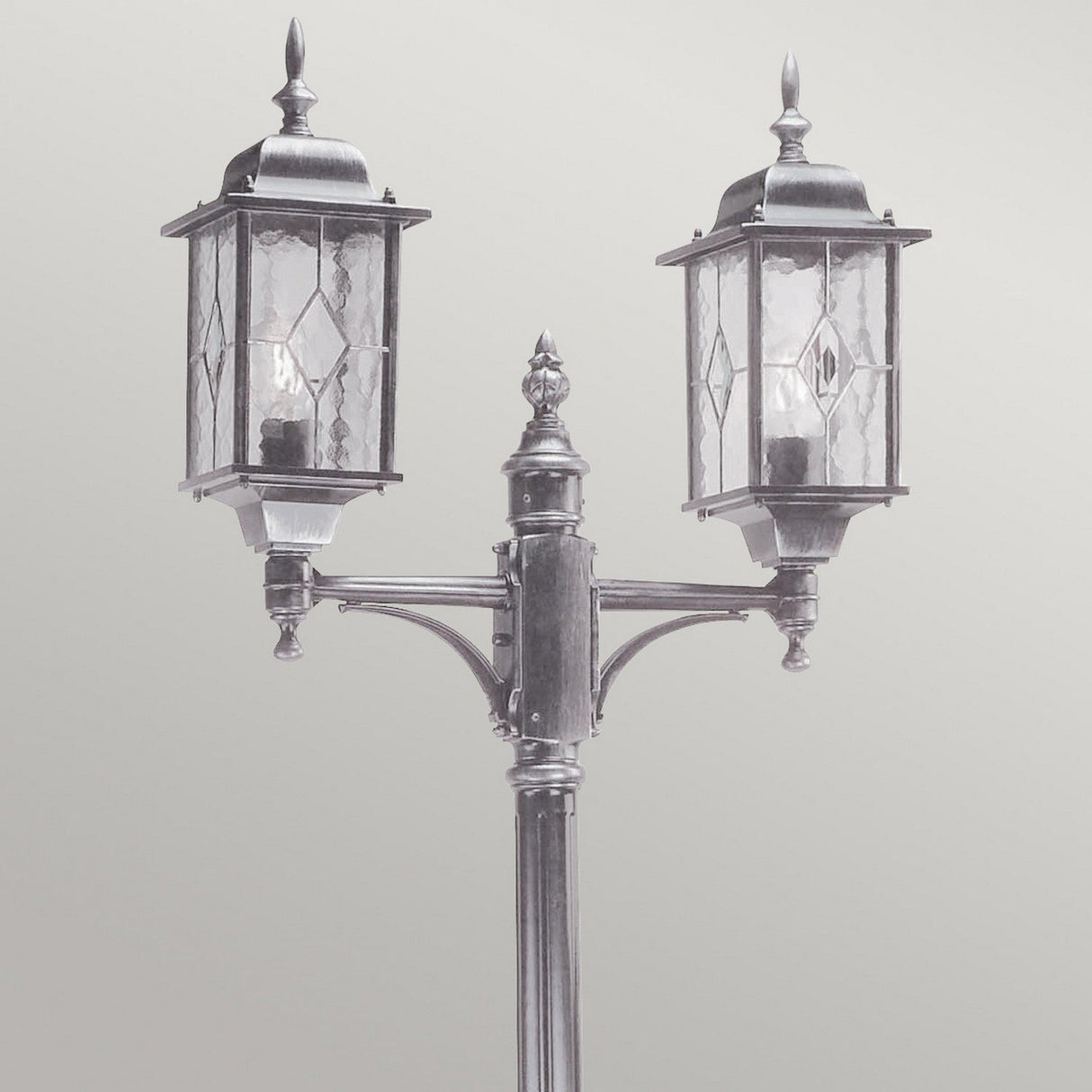 The Wexford 2 Light Lamp Post - Black/Silver offers vintage-style outdoor lighting with two lanterns, featuring decorative glass panels on a metal post with ornate detailing, set against a neutral gray background.
