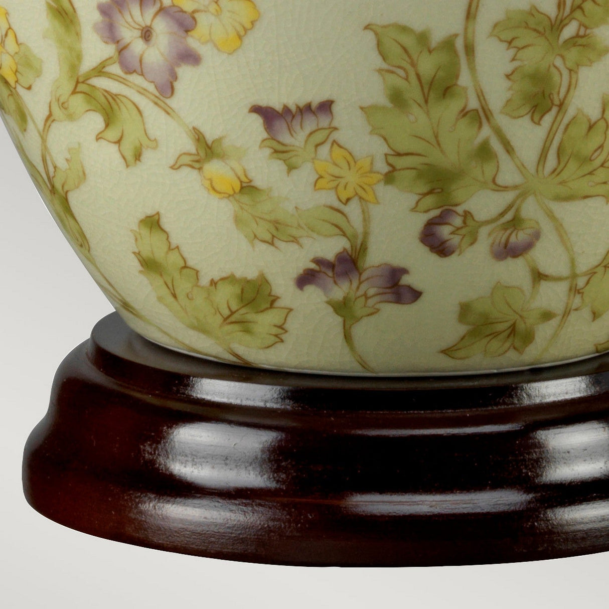 The Yellow Flowers 1 Light Table Lamp exhibits a delicate floral design featuring purple and yellow flowers intertwined with green leaves. It stands on a polished dark wood base, reminiscent of classic Chinese porcelain artistry, providing an elegant contrast to any plain, light-colored background.
