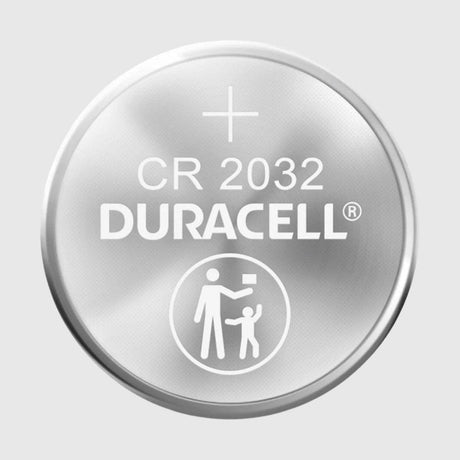Close-up of a Duracell CR 2032 coin cell battery. The top features the Duracell logo, battery type, and a safety icon showing an adult handing something to a child.