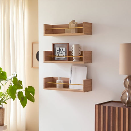 Set of minimalist wooden wall shelves displaying books, ceramics, and framed art, styled beside a tall plant for a clean, modern aesthetic.