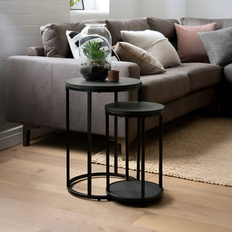 Pair of modern black nesting side tables placed beside a sofa, styled with plants and décor for a clean and functional living room accent.