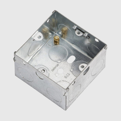 A metal electrical junction box with multiple knockout holes for wiring is shown. It has a square shape and pre-drilled screw holes for mounting.
