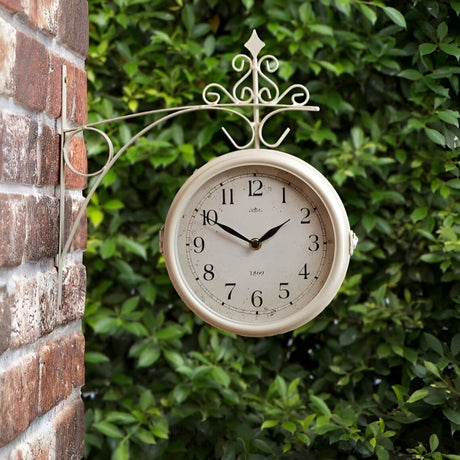 Outdoor vintage-style hanging clock mounted on a brick wall, framed by lush green foliage for a classic garden decor look.
