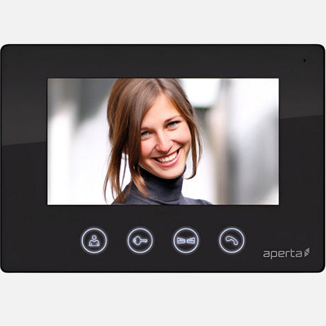 Video intercom screen showing a smiling person with long hair in a bun, wearing a gray turtleneck. The intercom has four buttons with icons below the screen, set in a white frame.