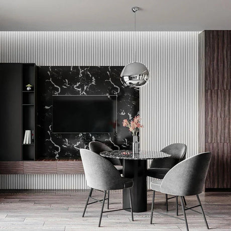 Modern dining area with marble wall, round black table, and grey upholstered chairs.