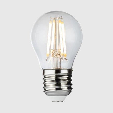A white LED light bulb with a metallic screw base is standing upright against a plain white background, casting a faint reflection beneath it.