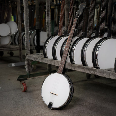 Row of banjos on stands in a workshop, with one banjo leaning in the foreground.