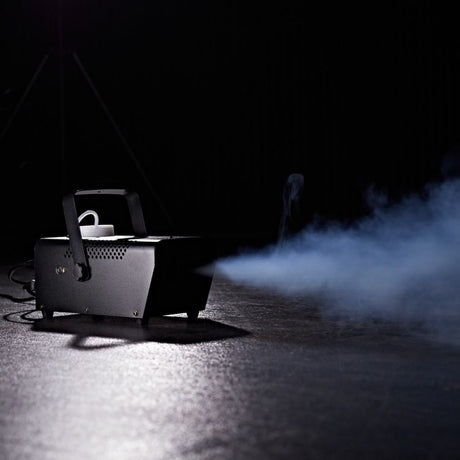 Compact haze machine emitting a soft, diffused mist onto a dark stage surface.