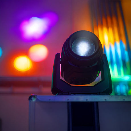 Colorful stage lighting fixture projecting vivid beams of light in a dark room, creating a dramatic atmosphere.