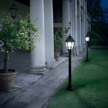 Classic black lampposts lighting a garden path beside a columned building.