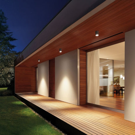Modern house exterior with recessed wall lights illuminating wooden deck.