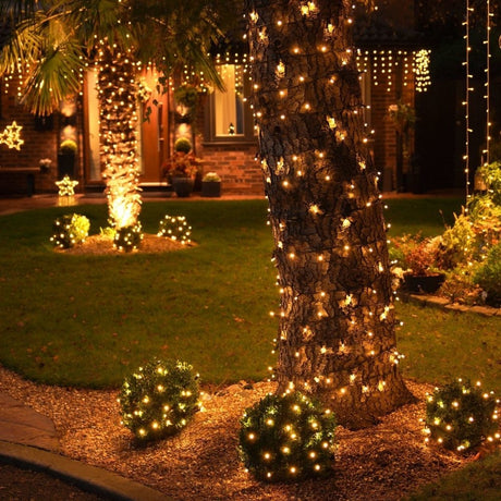 Outdoor trees wrapped in string lights creating a festive evening glow.