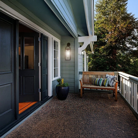 Front porch with wall-mounted light beside door and wooden bench.