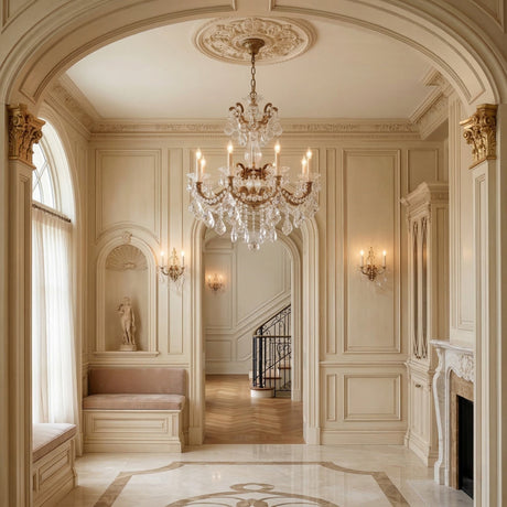 Elegant, cream-colored foyer with ornate molding, a Vienna 8 Light K9 Crystal Chandelier, arched doorway, marble floor, carved fireplace, wall sconces, large window with sheer curtains, and a niche featuring a classical statue.