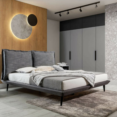 Contemporary bedroom with upholstered bed, geometric wall art, and warm lighting.