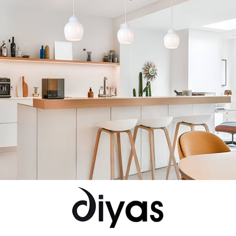Modern white kitchen with a wooden countertop, three white barstools, pendant lights, and various decor items on shelves. The word diyas is displayed at the bottom of the image.
