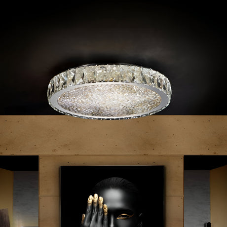 A circular crystal ceiling light illuminates a dimly lit room. Below, a black and gold artwork features a person with gold-painted fingers covering their mouth and face. The walls have a textured beige finish.