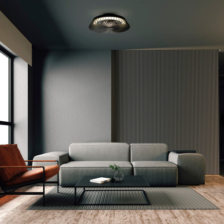 Mantra Himalaya Mini matt black LED ceiling fan light with retractable blades, mounted in a modern living room above a grey sofa and tan armchair.