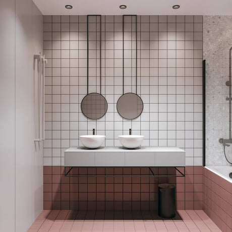 Black recessed downlights in the ceiling of a tiled bathroom with twin basins and two round mirrors