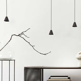 Rimini LED Cone Pendant Light in matt black, three small conical shades on black textile cables hanging at varying heights in a living room setting.