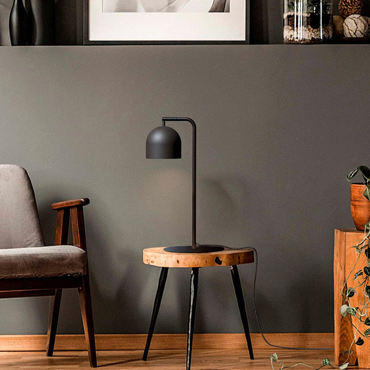 Rio Articulated Dome Adjustable Table Lamp in matt black iron, hook-arm design with dome shade, shown on a wooden side table in a living room setting.