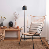 Rio 2 Light Dome Floor Lamp in matt black, slim stem and round base, shown beside a rattan chair in a living room with rug and side table.