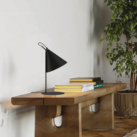 Rubi Cone Table Lamp in matt black with gold-lined conical shade and slim iron stem, shown on a wooden console table beside stacked books.