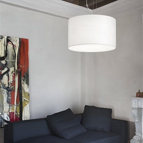 A modern living room highlights a black sofa with plush cushions beneath a Marquise 5 Light Pendant in white, its adjustable steel cables enhancing the contemporary look. An abstract painting in red, black, and beige tones adds vibrancy to the light gray walls, while a white fireplace sits in the corner.