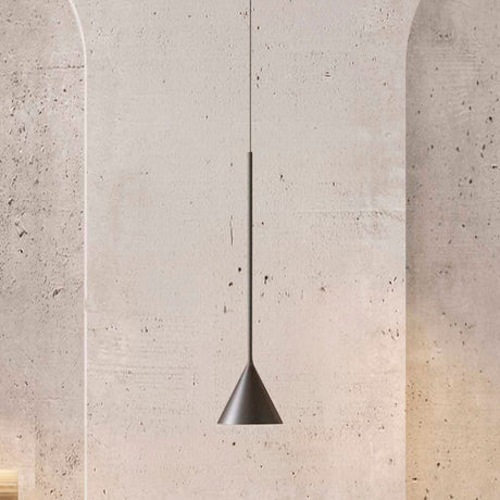 Rubi Mono Cone Pendant in matt black with a slim stem and small cone shade, hung against a textured concrete wall.