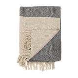 Matt Throw in beige, folded to show a plain open weave on one side and a flecked charcoal zigzag weave on the reverse, with long loose fringe, on a white background.